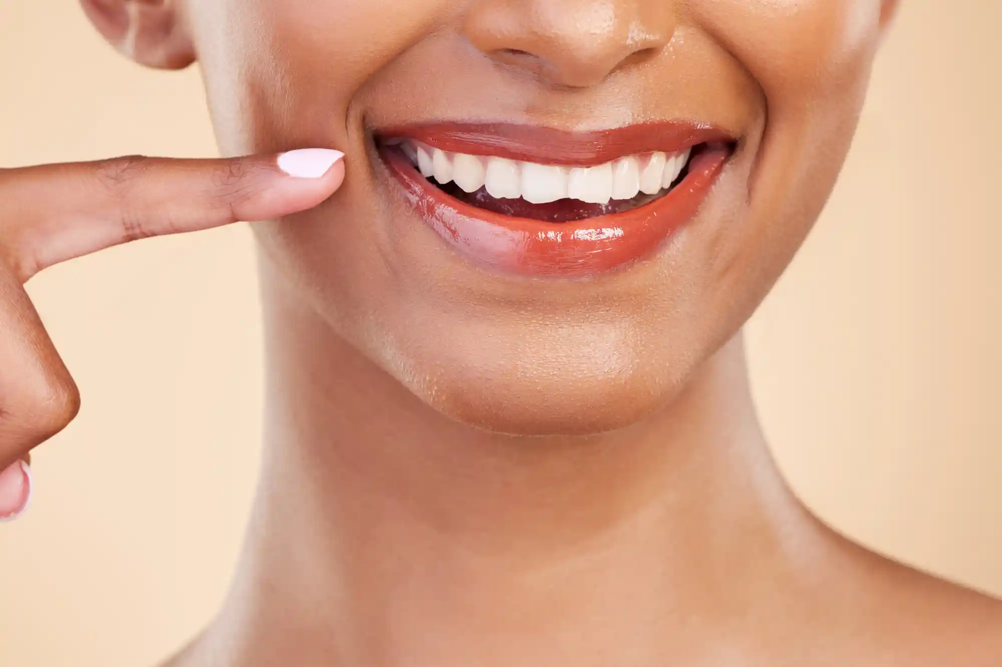 A woman pointing at her smile, improved by cosmetic dentistry in Rexburg